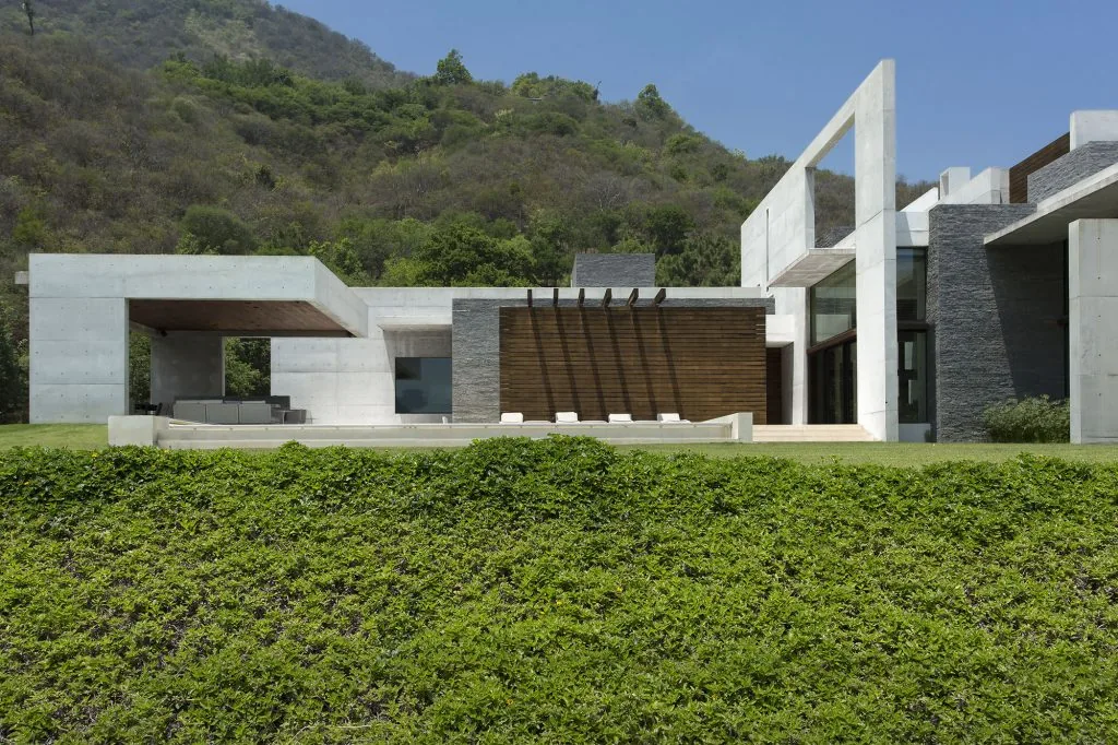 House near Monterrey with a rectangular concrete frame and wood accents, set against a mountain backdrop.