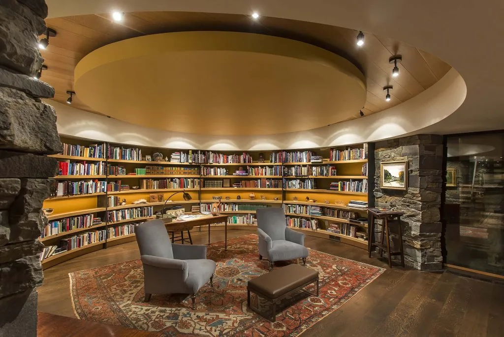 Curved library with extensive built-in shelves and a warm circular ceiling design