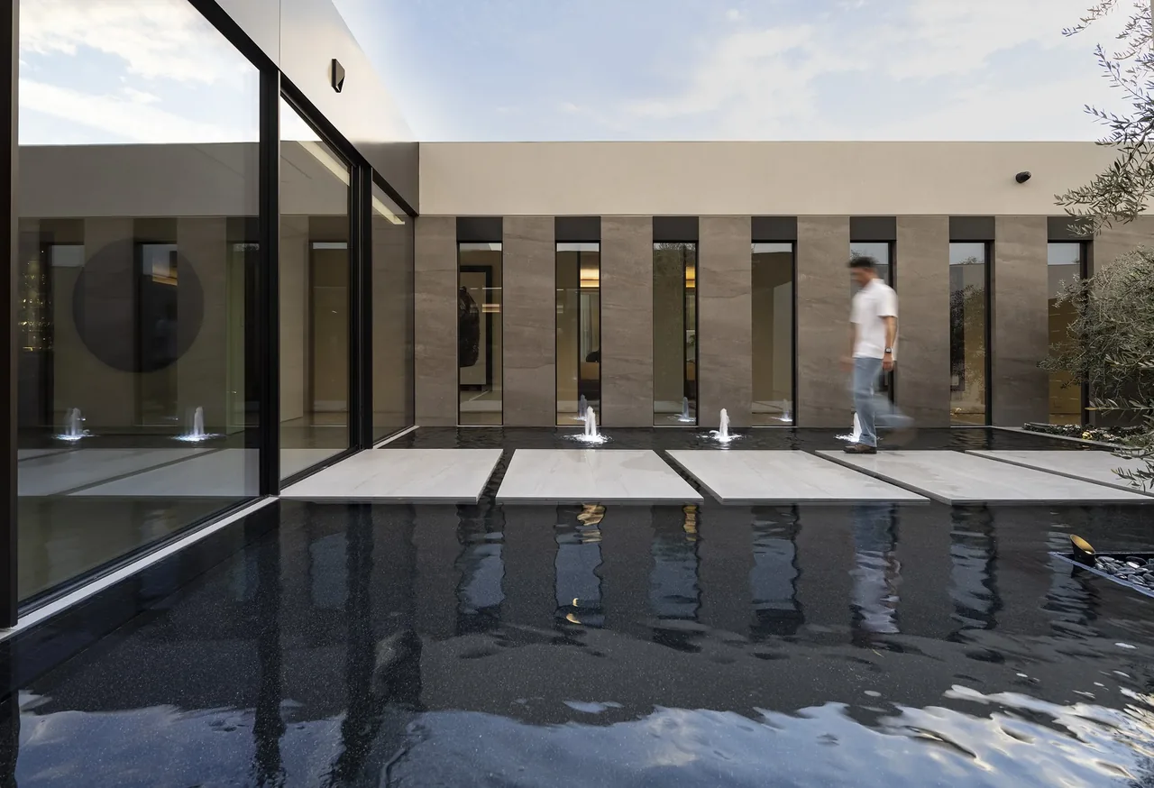 The Bighorn project features a sleek courtyard with stepping stones set over a reflecting pool and vertical windows on the surrounding facade.