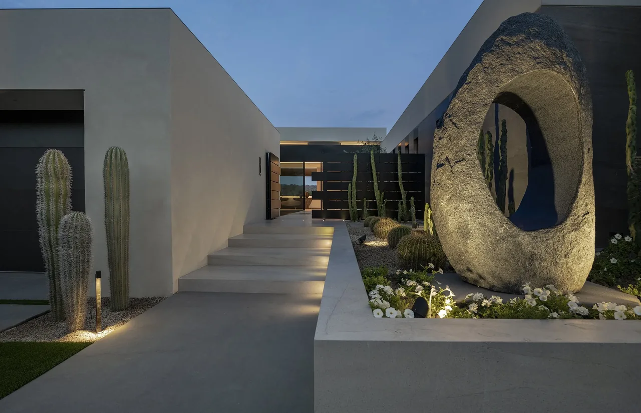 The bighorn project by Whipple Russell Architects features a modern entry with desert landscaping and a striking stone sculpture.