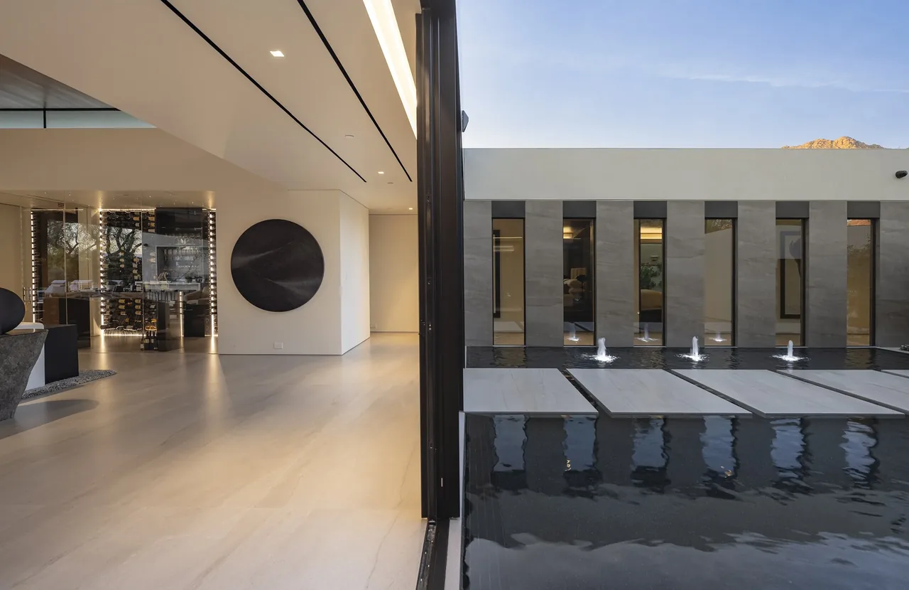Modern courtyard features a reflecting pool with water fountains and stepping stone path by Whipple Russell Architects.