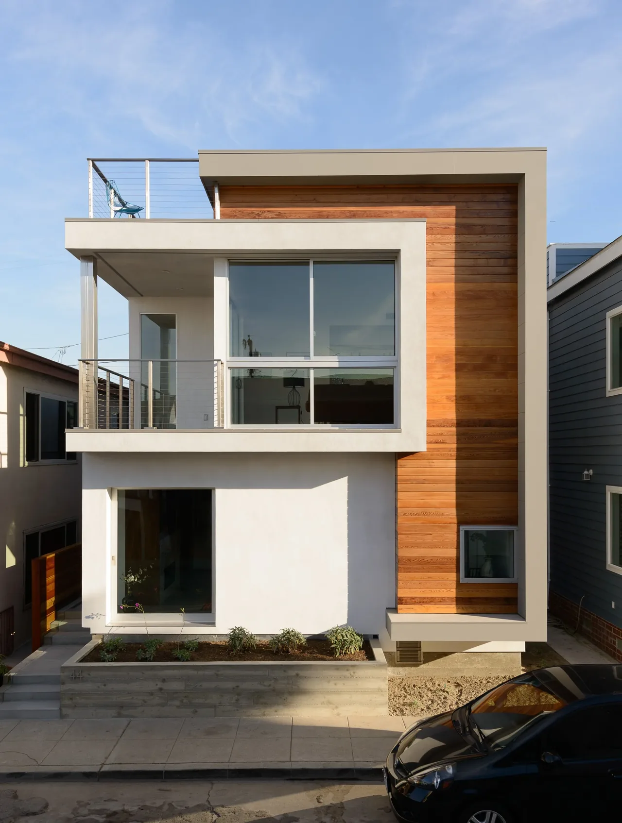 61ST urban residence by Studio LeMaster features wood siding, large windows, and a balcony with cable railing.