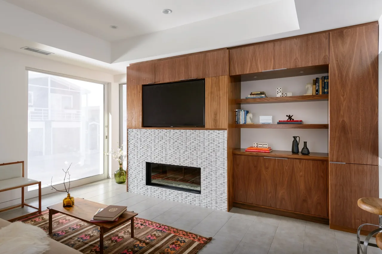 Living room features wood cabinetry with open shelves, a mosaic tile fireplace, and a large sliding glass door for natural light.
