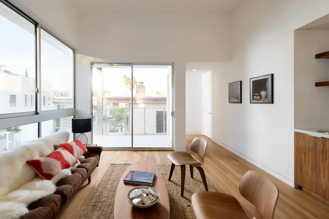Living room features large sliding glass door to balcony, wood flooring, and midcentury modern style furniture.