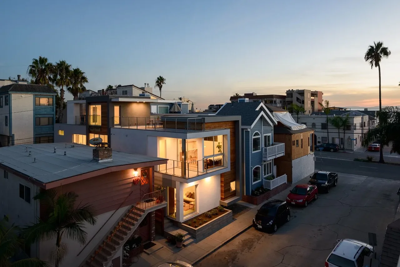 Modern residential building with large windows and outdoor staircase, lit in the evening in Los Angeles.