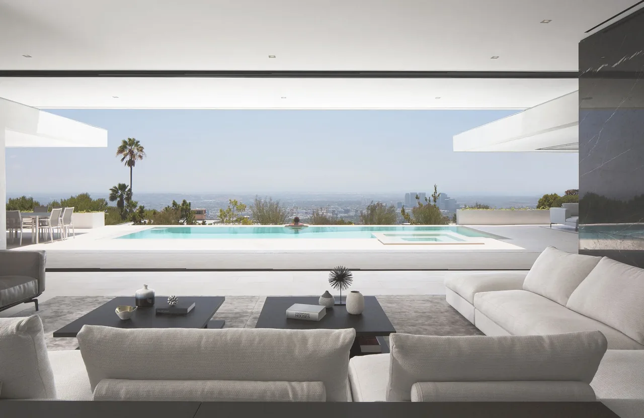 Living room opens directly to an infinity pool with a cityscape in the background.