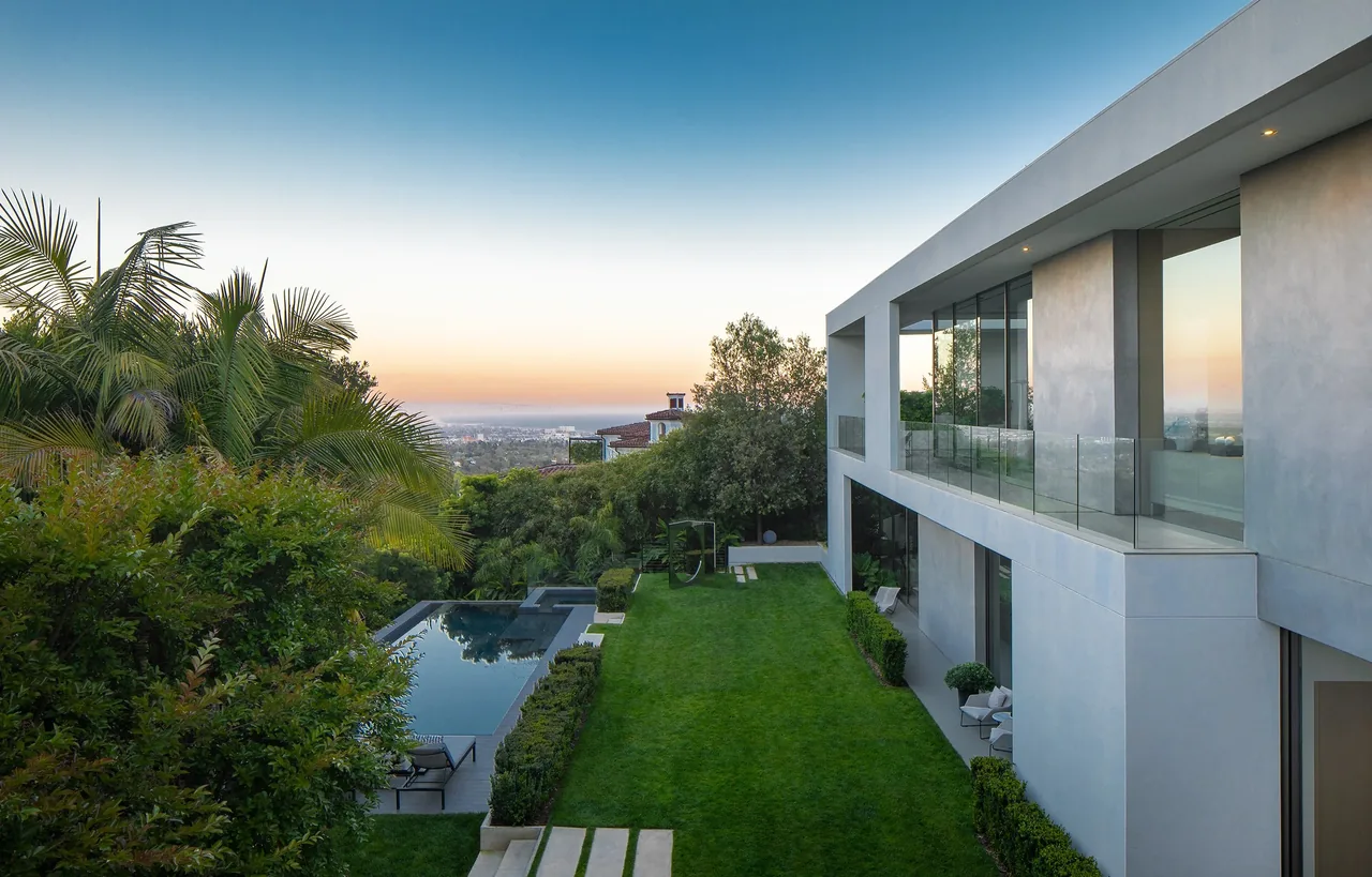 The aMahouse by XTEN Architecture features a modern exterior with large glass doors and a balcony overlooking a pool and garden in Los Angeles.