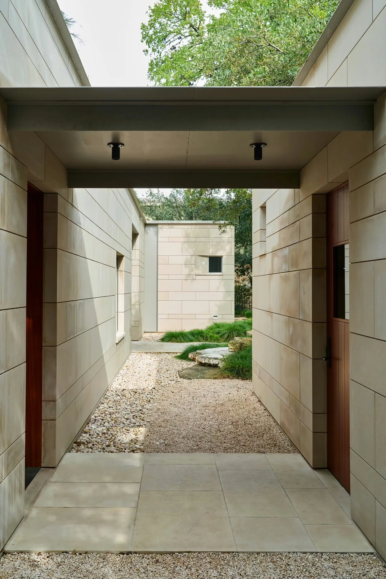Exterior passage between sections of the Residence on Mount Barker featuring light stone cladding and gravel ground.