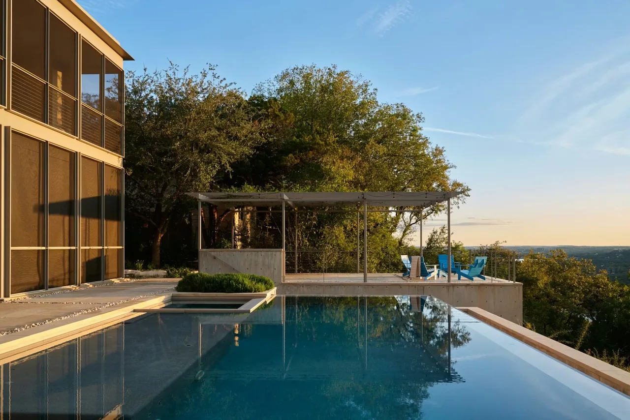 The Residence on Mount Barker features a pool with a concrete deck and a modern pergola seating area surrounded by lush greenery.