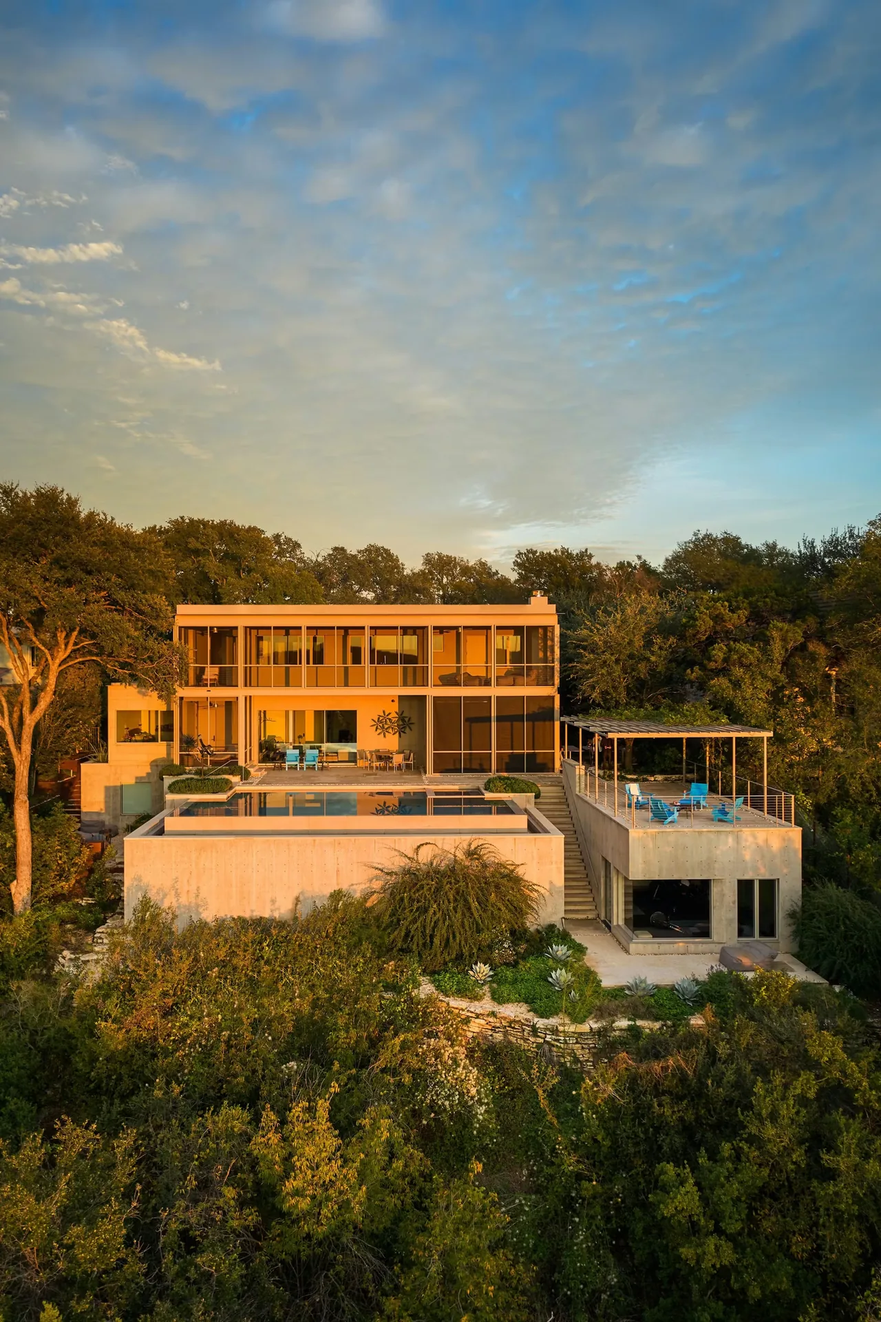 Residence on Mount Barker features a flat roof, extensive glazing, and an infinity pool overlooking a wooded hillside.