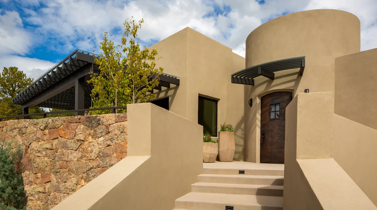 The Cummings project features a modern-style entrance with stucco walls, stone accents, and a metal door with an arched metal awning.