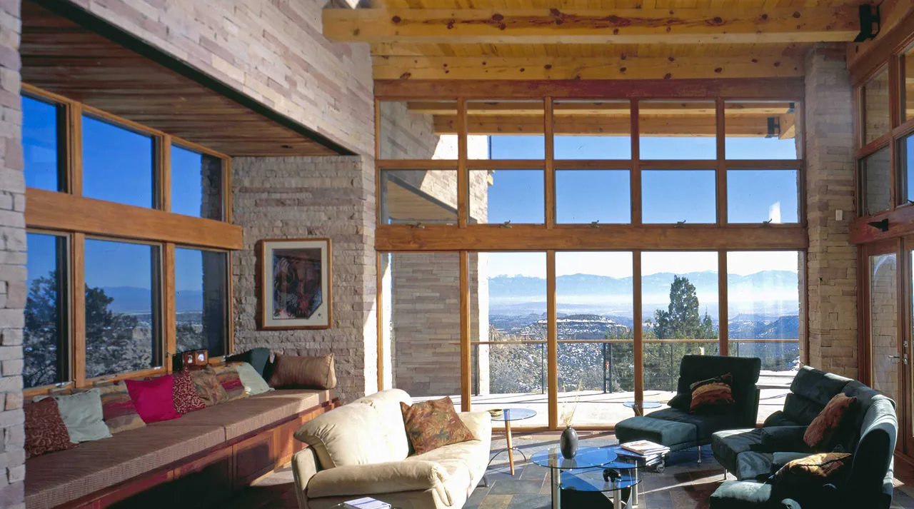 Living room with floor-to-ceiling wood-framed windows and exposed wooden ceiling beams.