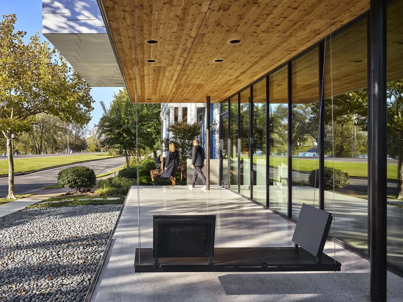 The Civitas project features a porch with floor-to-ceiling glazing and a suspended bench under a wood-paneled ceiling.