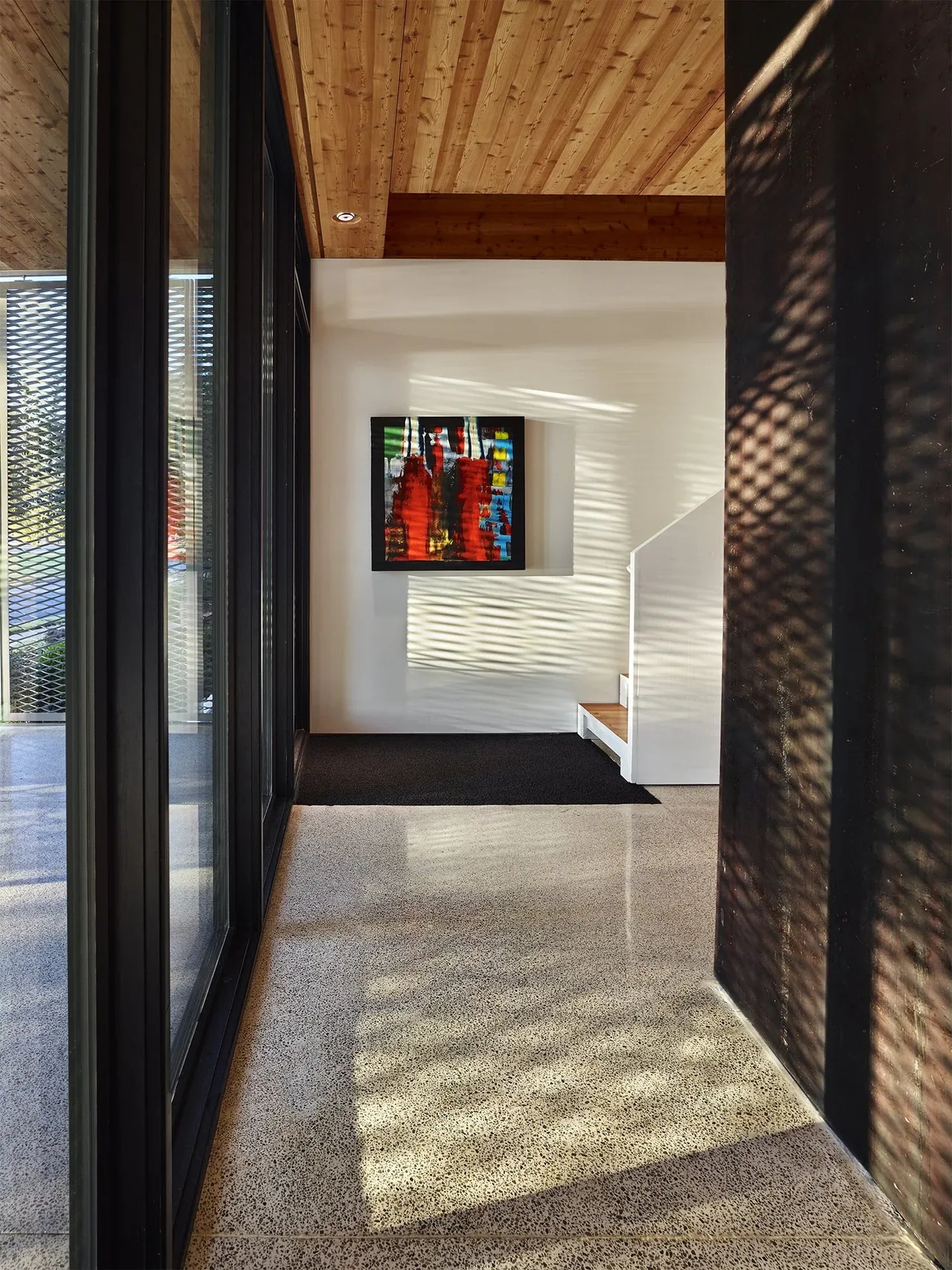 Entry hallway features polished concrete flooring, black window frames, and wood-paneled ceiling with recessed lighting.