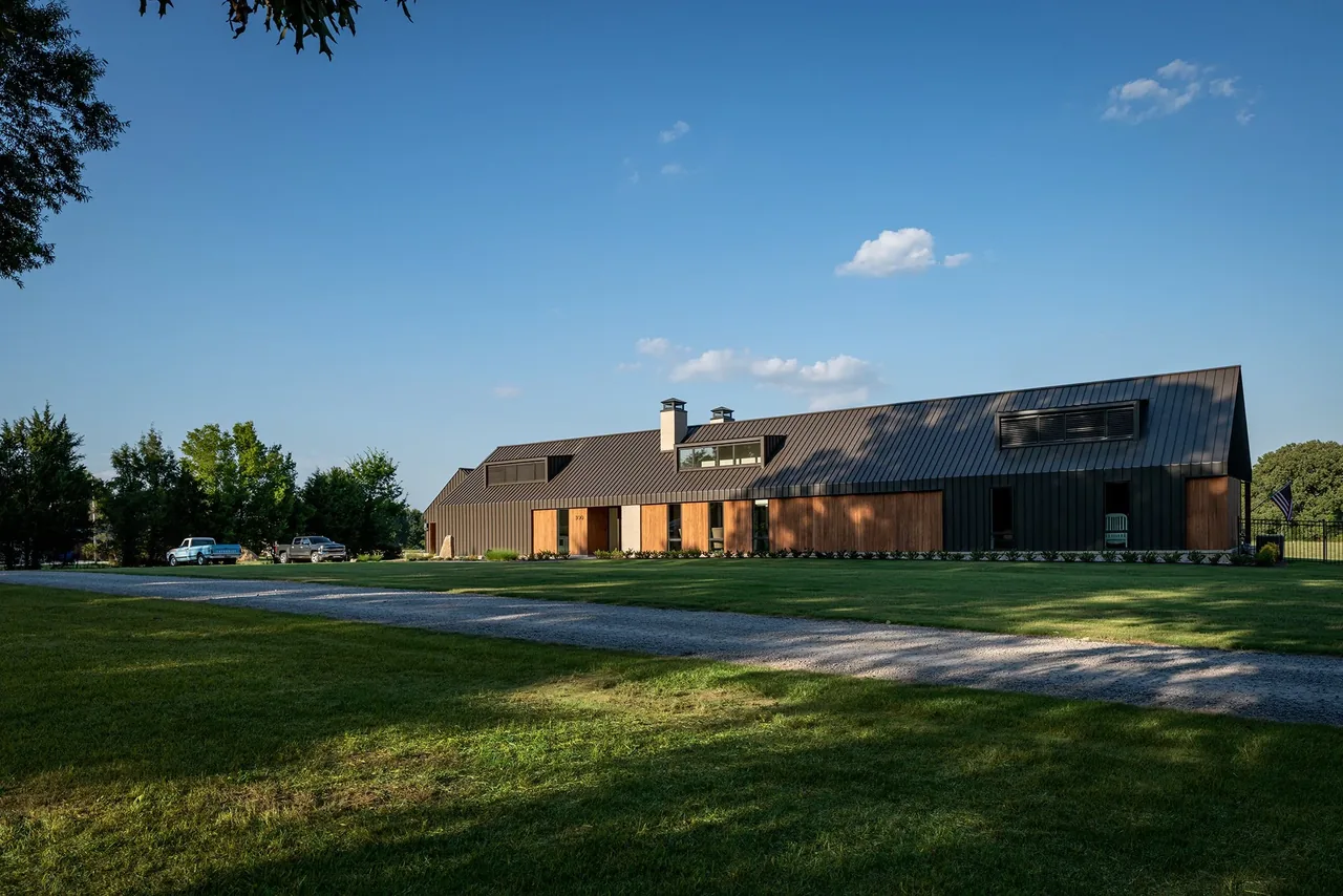 Fleetview Residence features a blend of wood and black metal siding with large window openings under a steep gable roof.