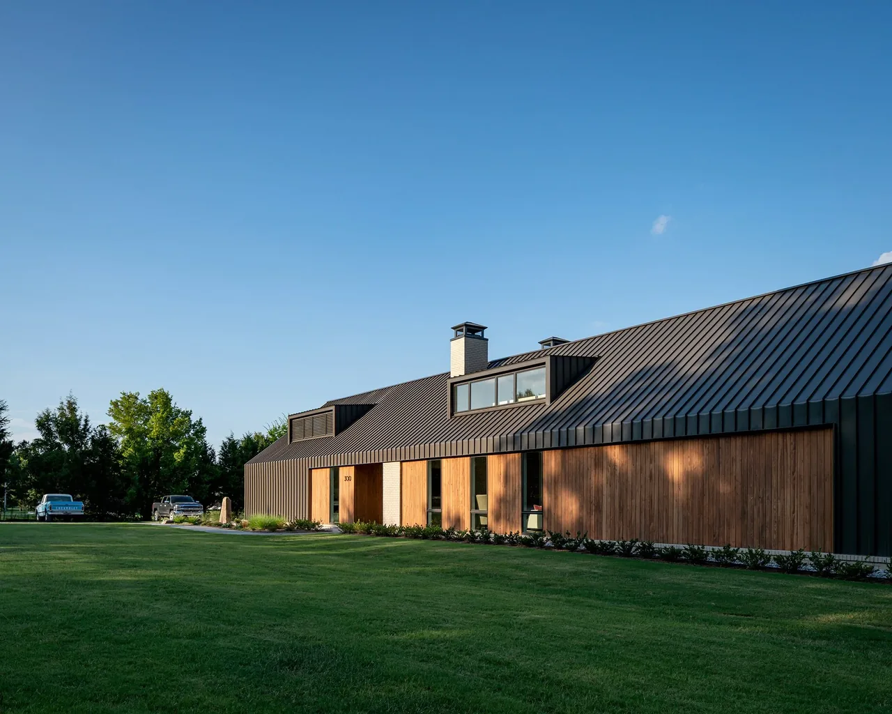 Fleetview Residence features a steeply pitched standing seam metal roof combined with vertical wood siding.