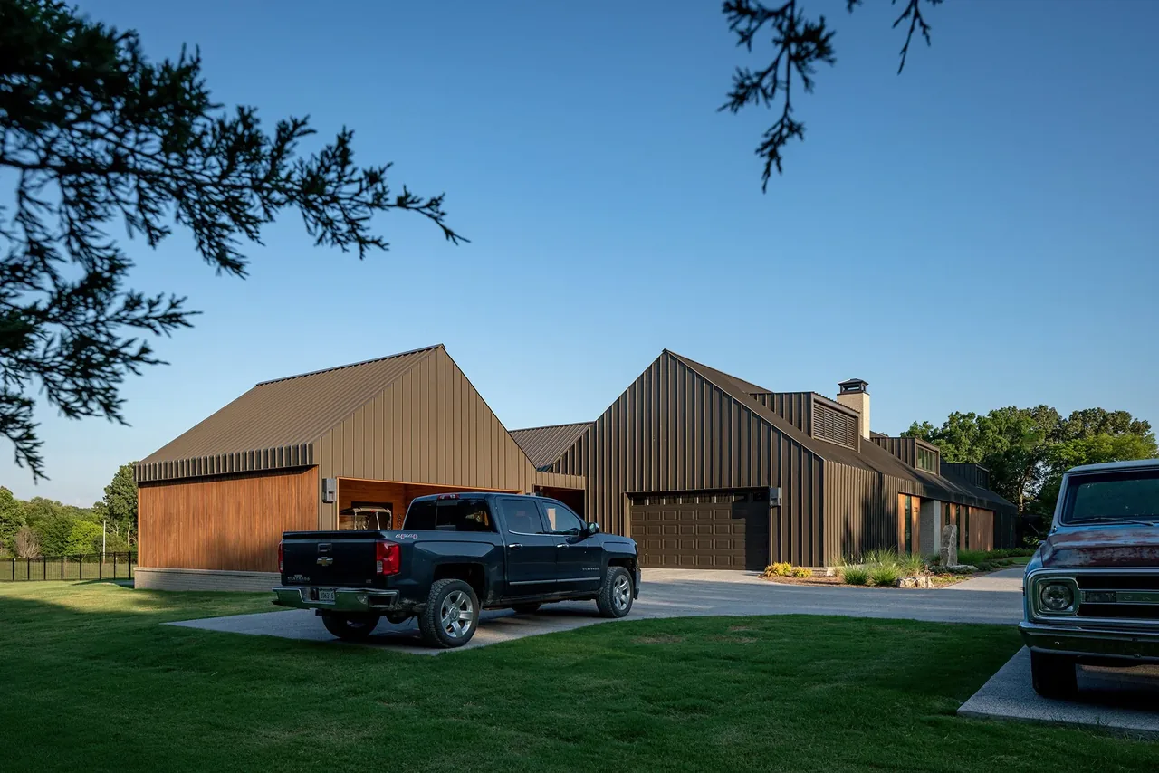 Fleetview Residence features dark metal siding and horizontal wood panels with a steep roof pitch and a large driveway.