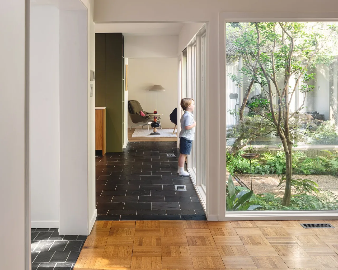 Interior hallway with parquet wood floor and large window overlooking a landscaped courtyard in Russell Residence.
