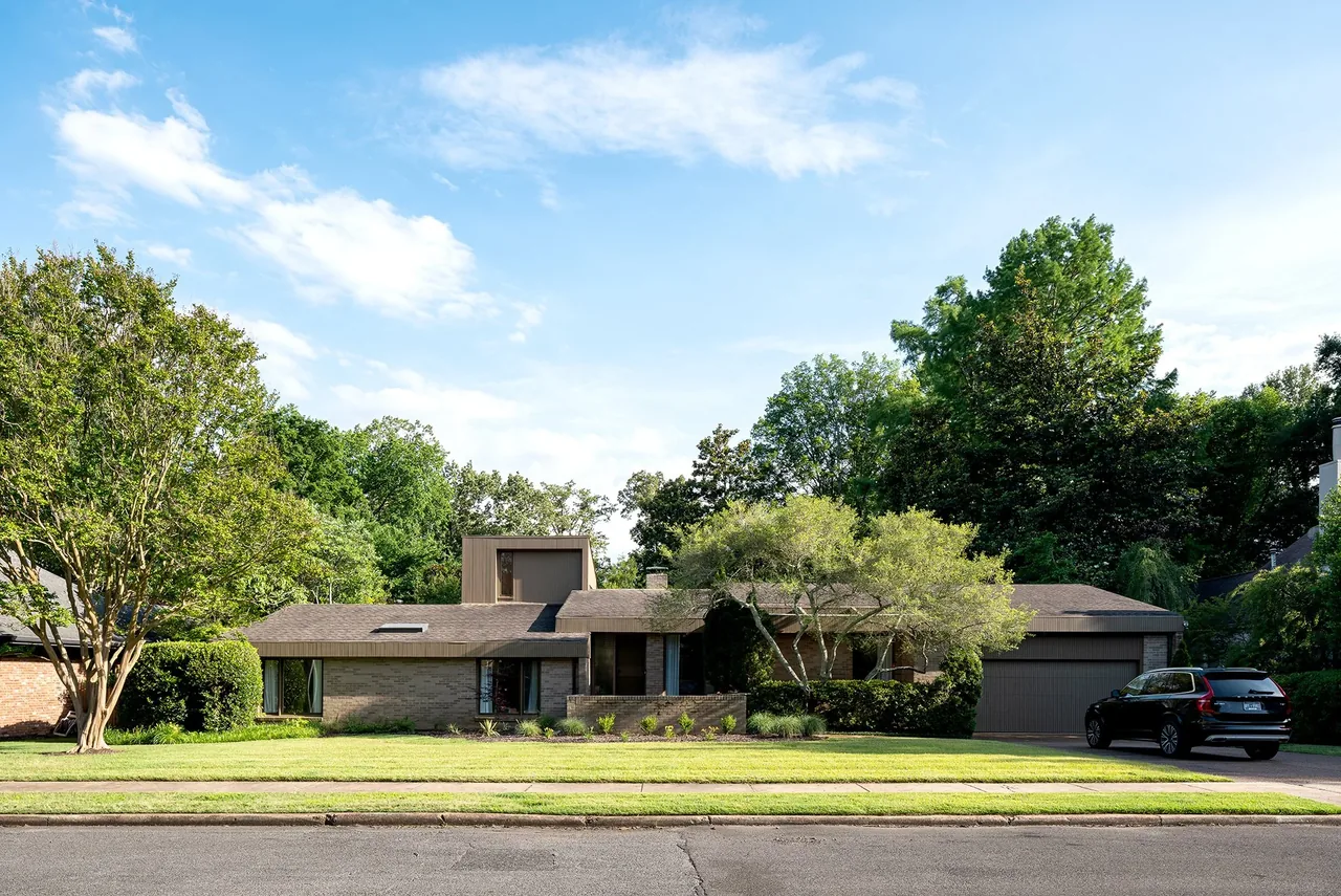 The Russell Residence is a midcentury modern house with a combination of flat and low-pitched roofs and an attached garage.