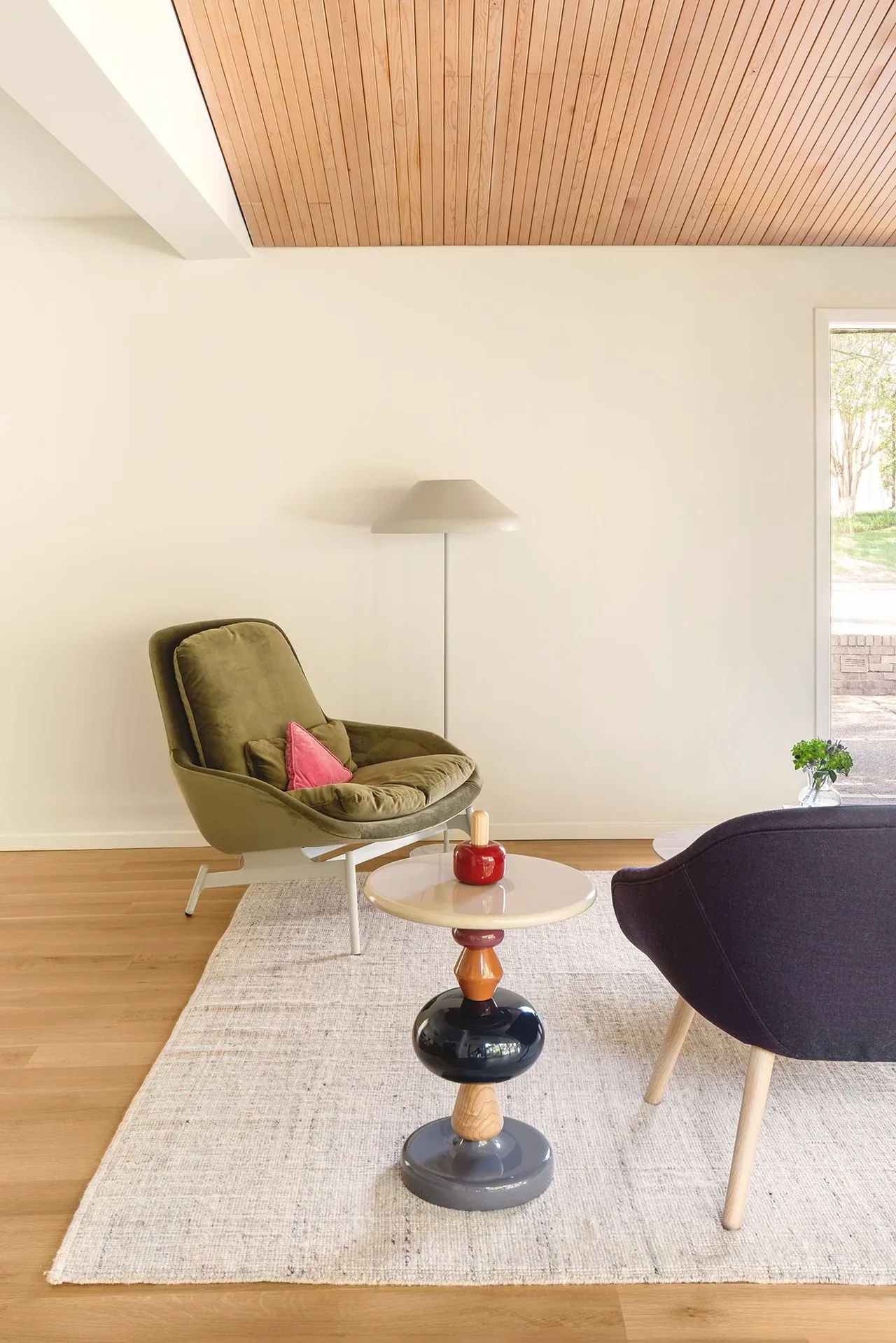 Living area features a wood-paneled ceiling and a vibrant multi-colored side table between two lounge chairs.