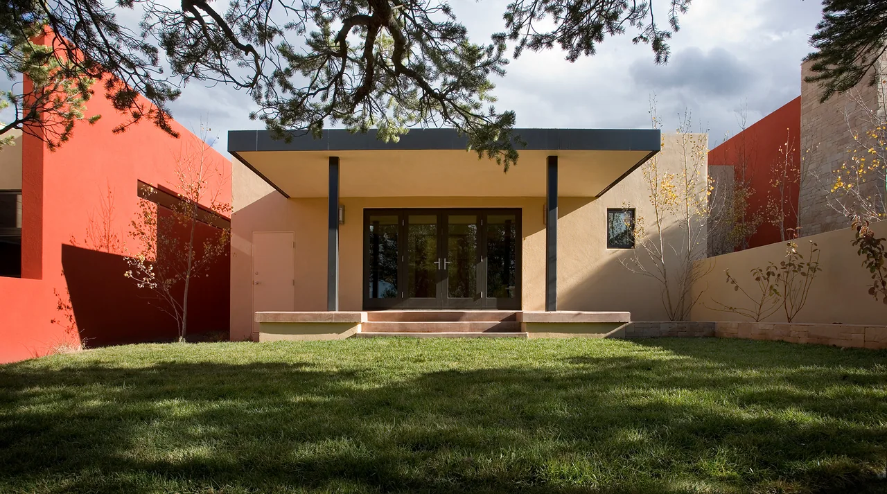 Rear exterior of Lehman project featuring an orange accent wall, black window frames, and a covered patio with steps.