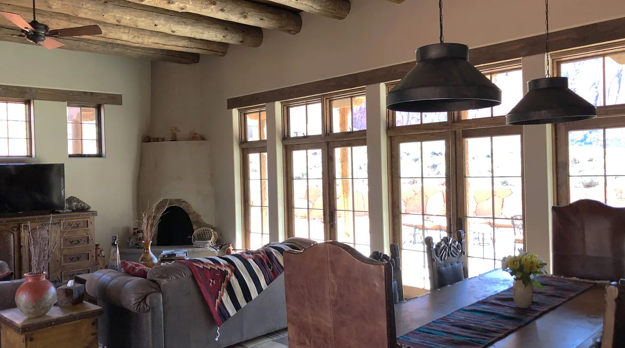 Southwestern style living and dining area with wood-beamed ceiling and kiva fireplace in the Applegate Residence.