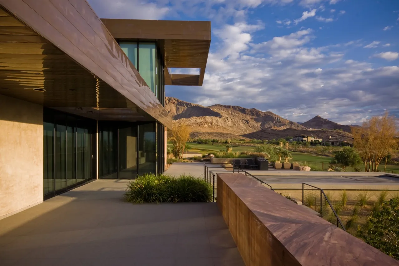 Copperhaus features large glass walls and an expansive outdoor patio with mountain views in a desert-like setting.