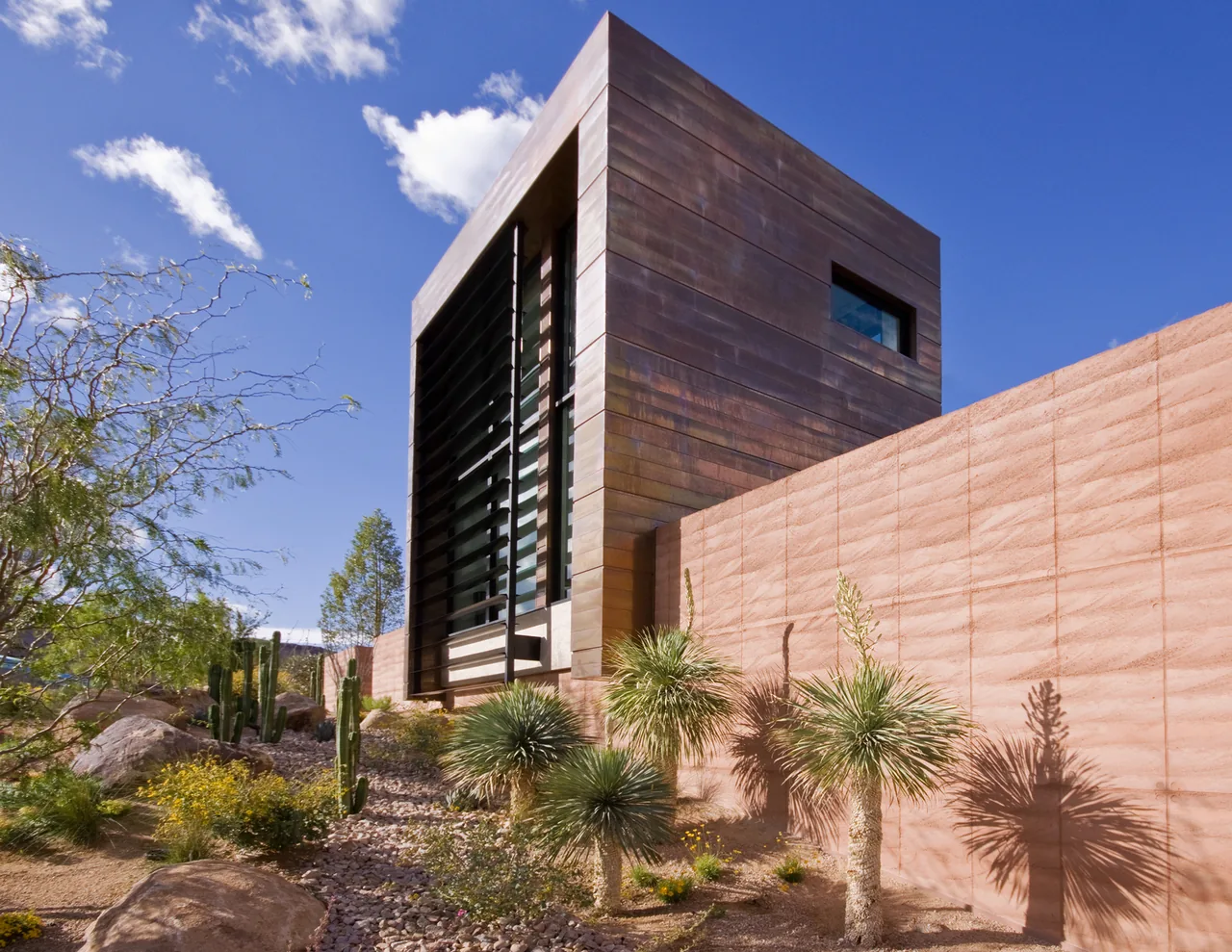 Copperhaus features a copper-paneled exterior with desert landscaping including cacti and small trees.