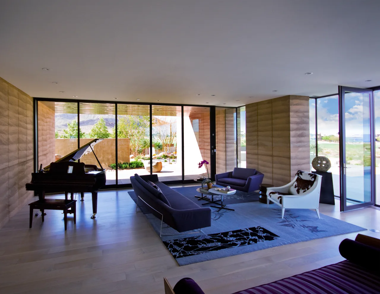 Living room with floor-to-ceiling glazing offers views of the desert garden and mountain landscape.