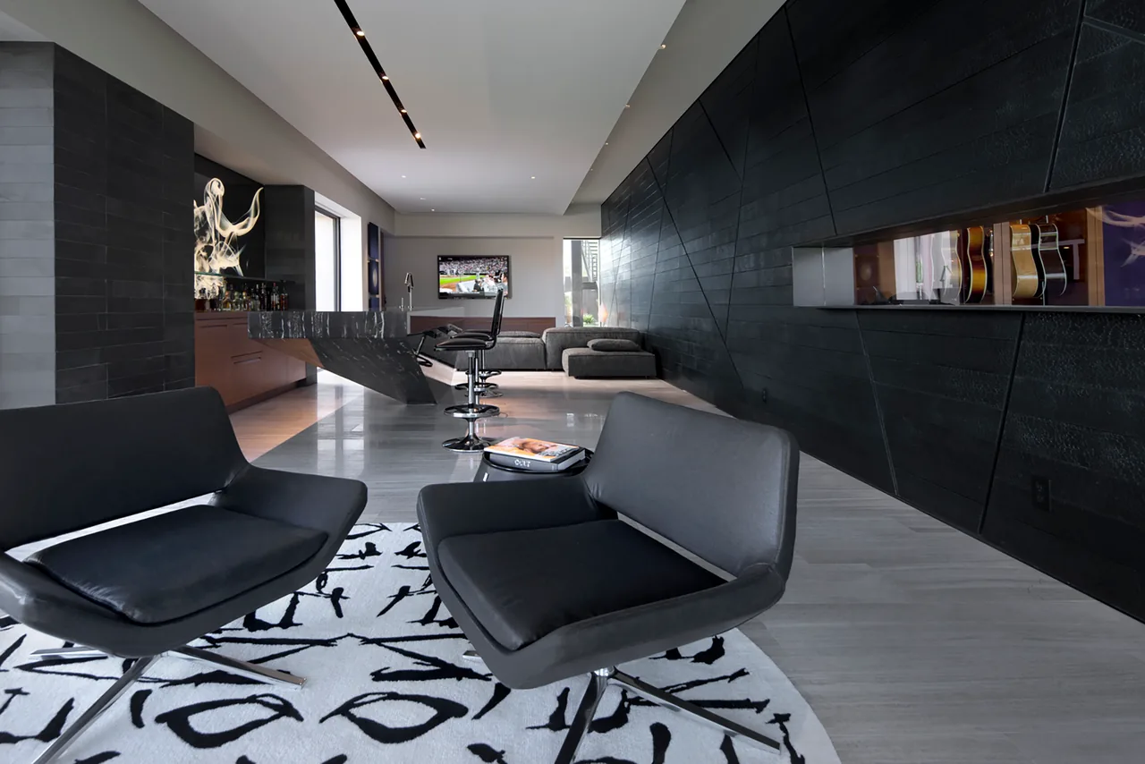 Interior view of tresARCA living area featuring a geometric black wood accent wall and a floating dining table.
