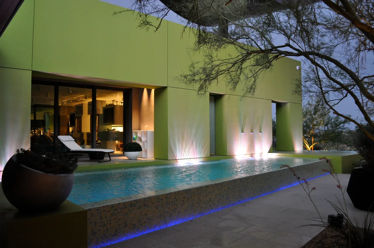 J2 Residence features a modern exterior with a sleek pool and illuminated water features at dusk.