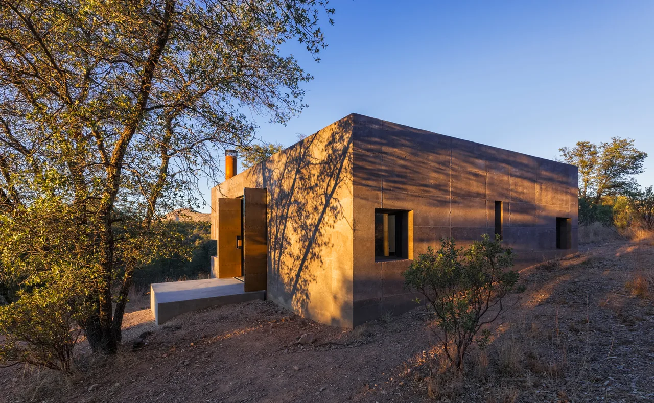Casa Caldera features a rectangular structure clad in weathered steel blending with its natural surroundings.