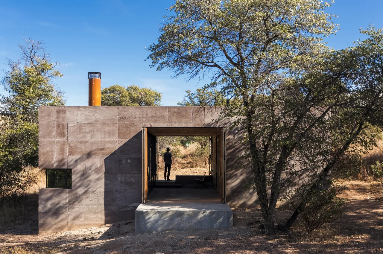 Casa Caldera by Dust Architects features a rectangular concrete volume with a large open rectangular passage framing views of the surrounding nature.