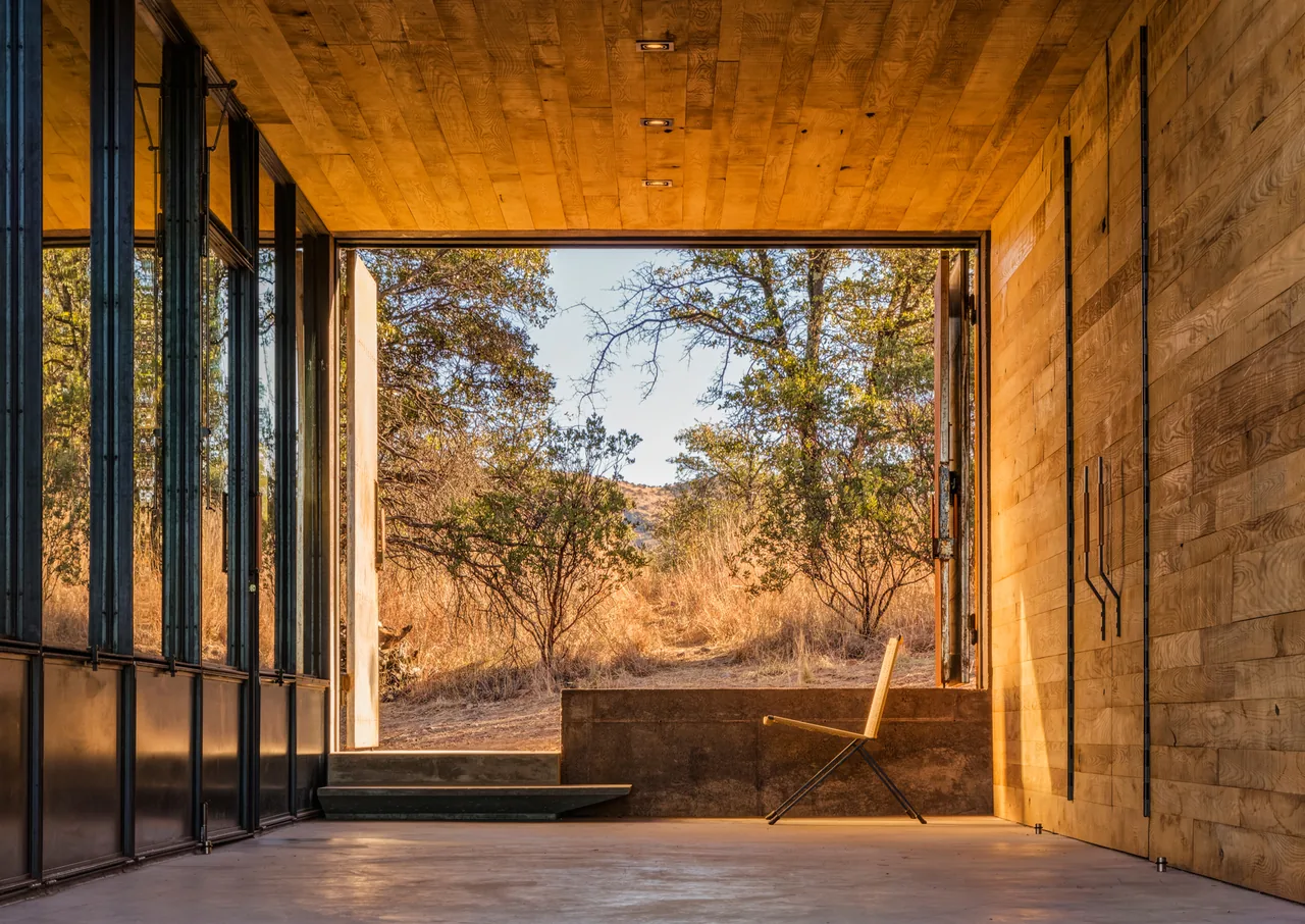 Casa Caldera features a recessed entry with a large rectangular opening framing nature views by Dust Architects.
