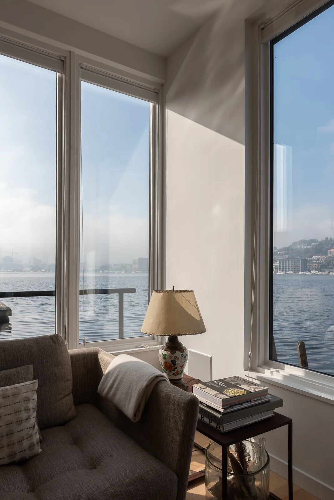 Living room corner with large windows overlooking the lake at the Lake Union Floating Home.