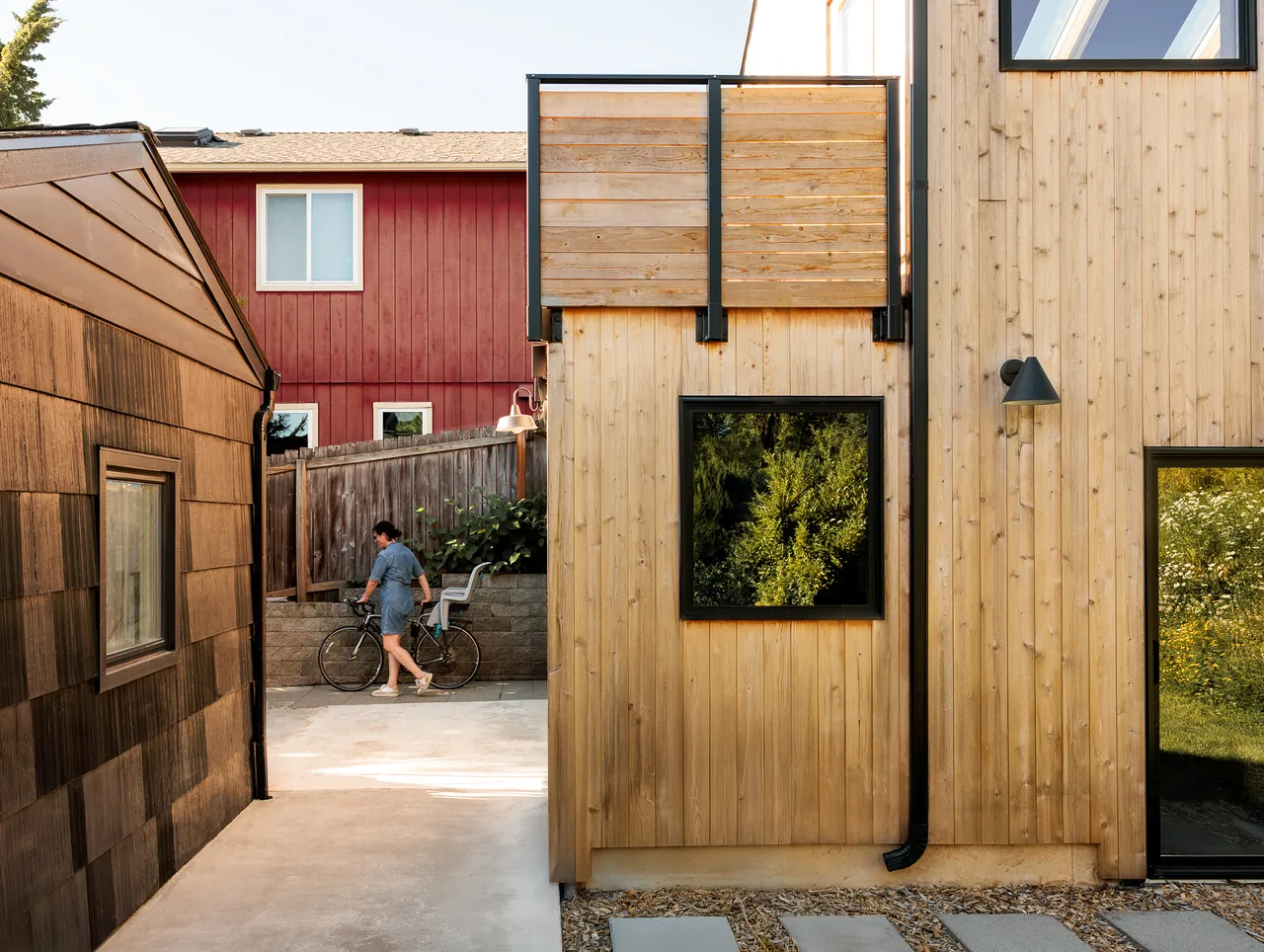 The Moonwave DADU features natural wood siding, black window frames, and a small balcony with wood railings.