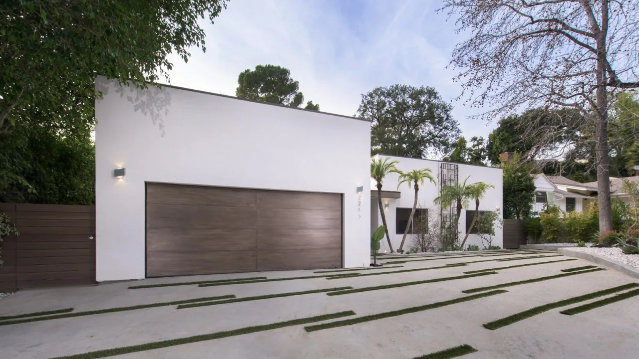The 2213 Roscomare project features a flat-roofed modern exterior with a large wooden garage door and a striped driveway with embedded grass strips.