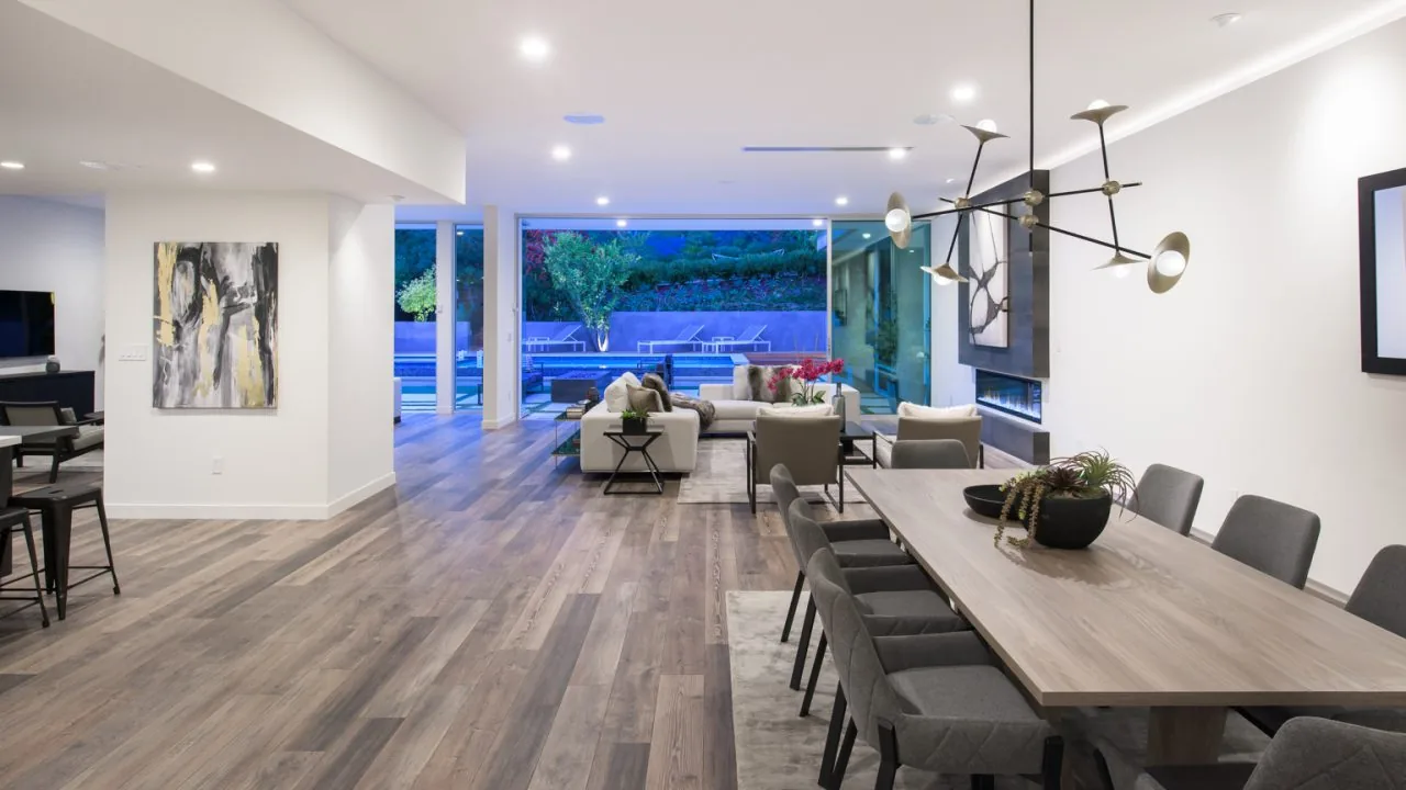 Open floor plan with dining area, living room, and large sliding glass door leading to outdoor pool and seating area.