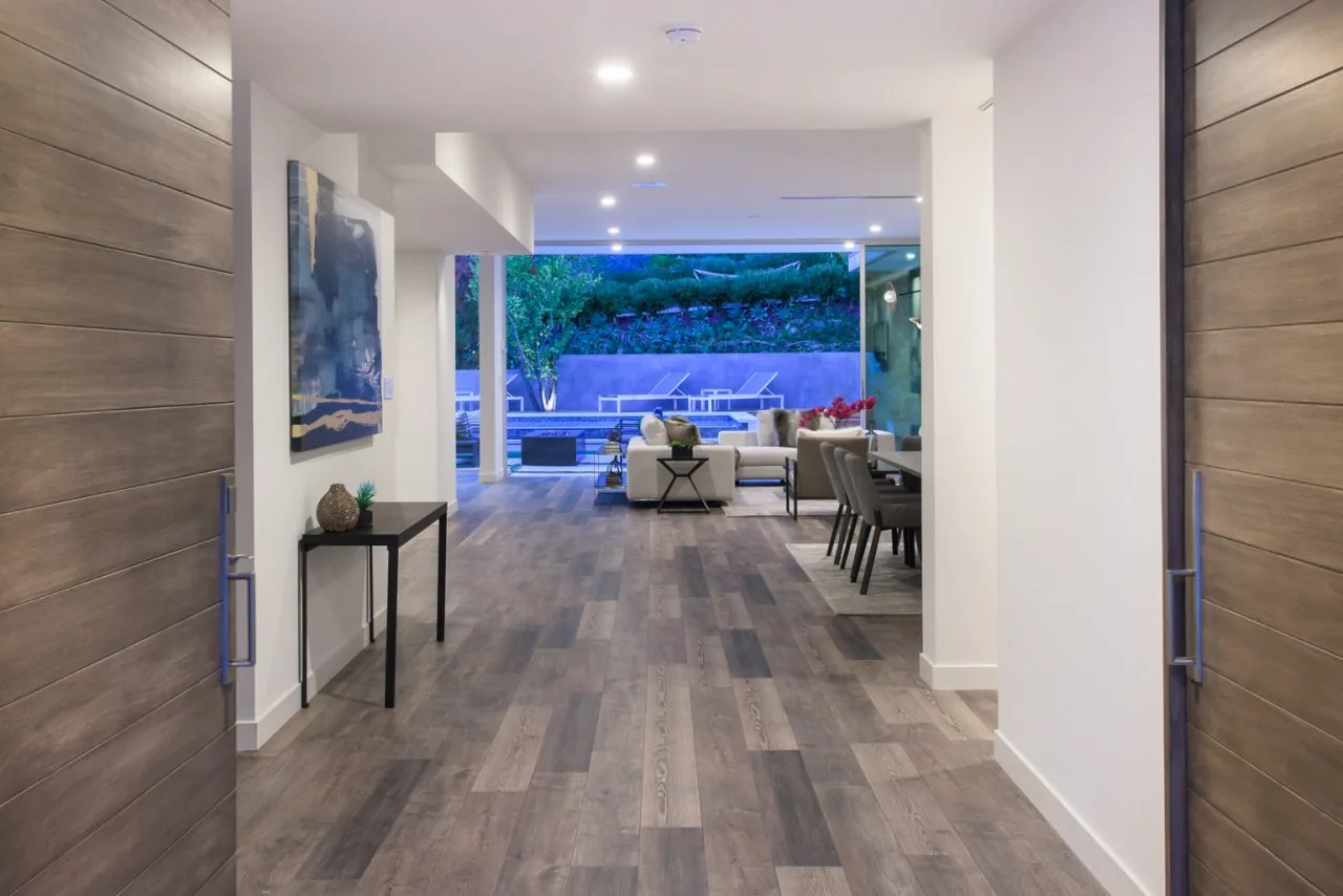 Interior view from hallway to living and dining spaces with large sliding glass doors leading outside at 2213 Roscomare.