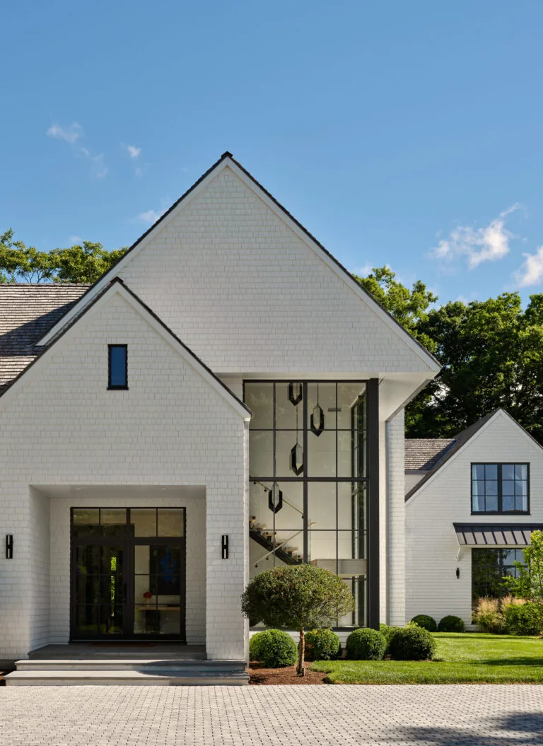 The Bauhaus Farmhouse features white brick exterior with black window frames and a large glass stairwell, designed by Austin Patterson Disston Architects.