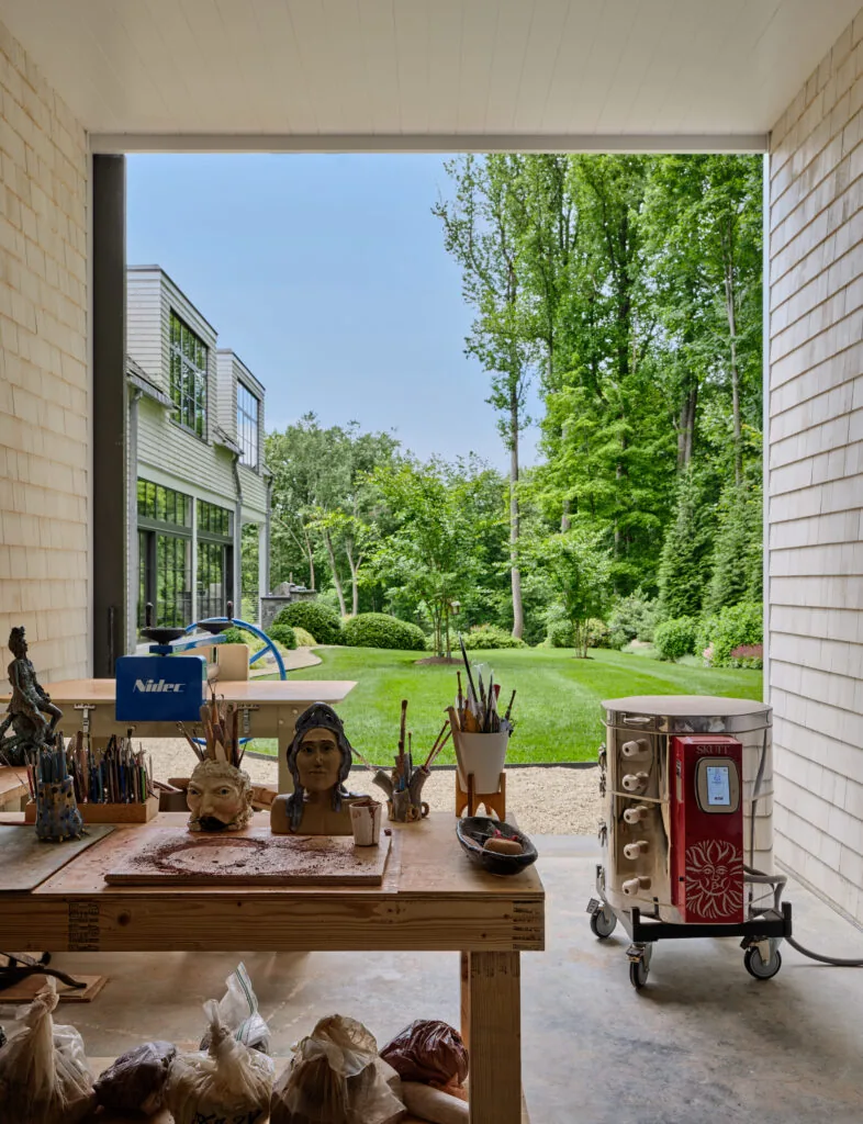 The workshop area in the home's covered garage opens to a landscaped backyard with lawn and trees.
