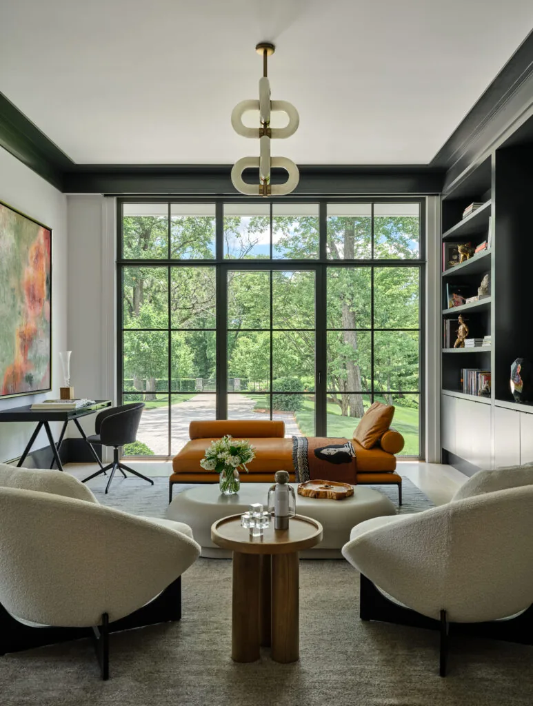 Modern-style living room with floor-to-ceiling black window frames and built-in shelving, designed by Austin Patterson Disston Architects.