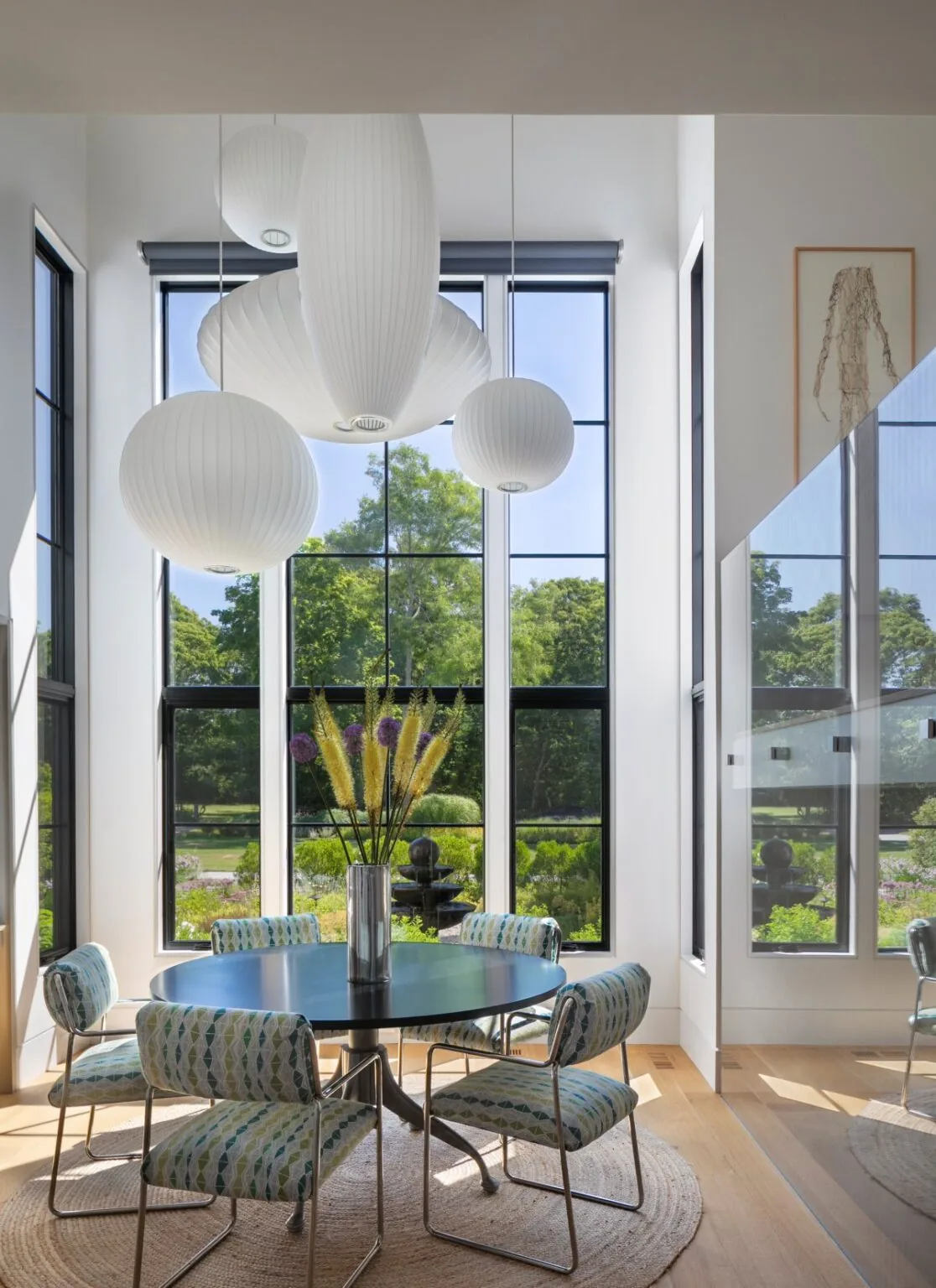 Dining area with large black-framed windows and modern pendant lighting in the Vernacular Redefined project.