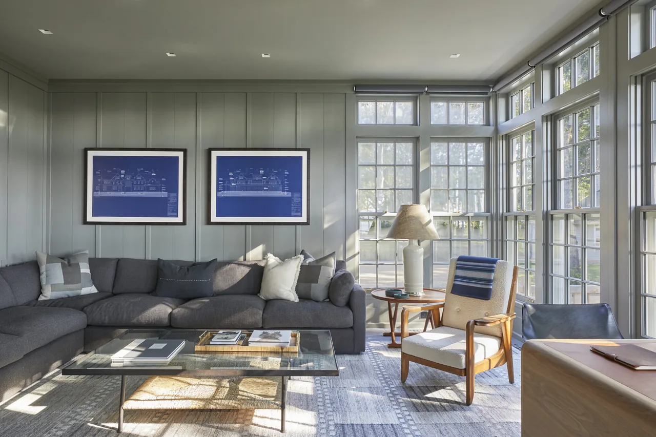 Bright living room features a gray sectional sofa and multiple tall windows with divided lites on two sides.