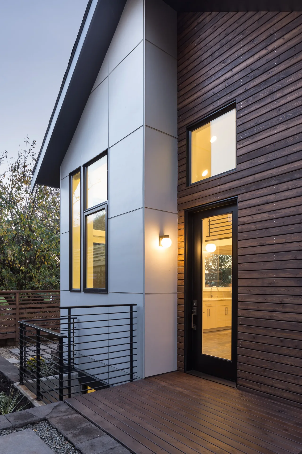 The exterior of Project 335 DADU shows dark horizontal wood siding and white paneling with black window frames and a glass door.