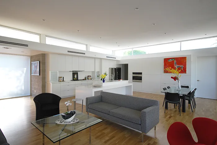 Modern open living and kitchen area in the Pulaski residence with natural wood flooring and clerestory windows.