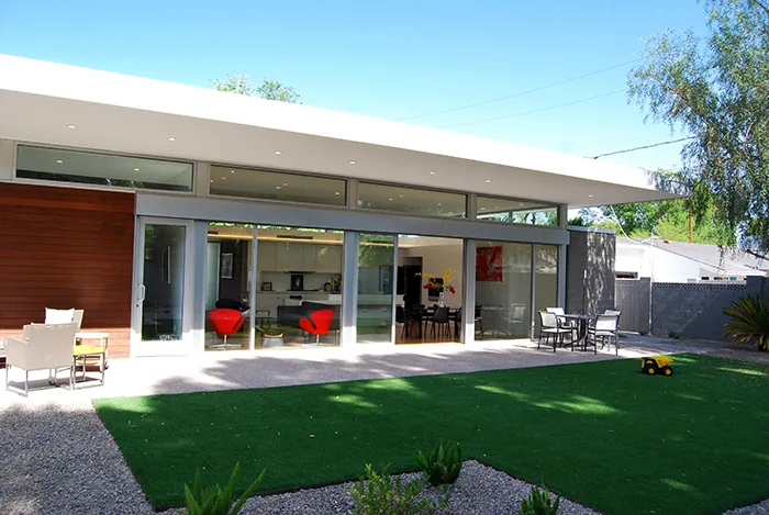 The Pulaski residence features a modern exterior with large sliding glass doors and clerestory windows above, opening to a patio and lawn.