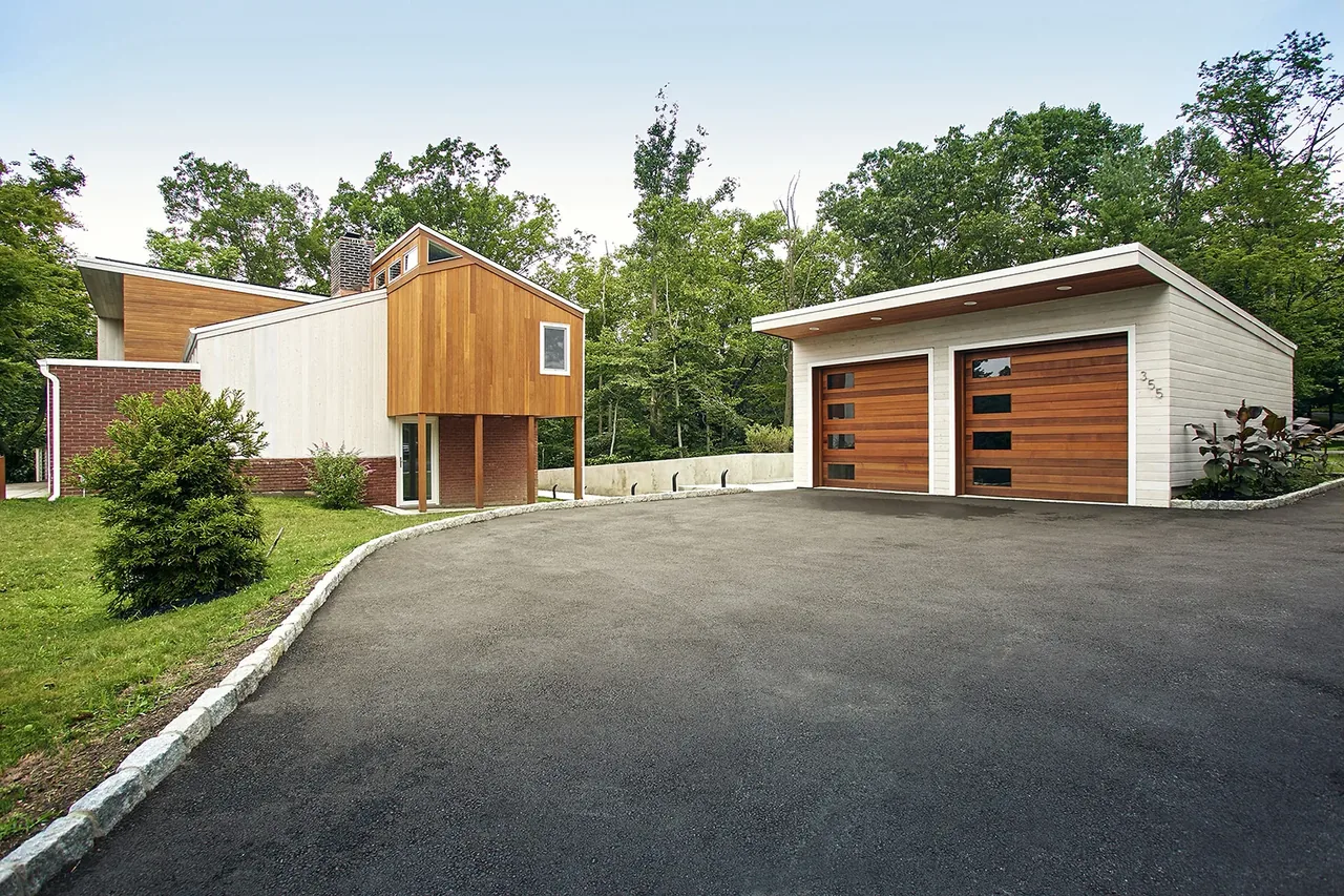 Scoppettone/Leach House renovated with mid-century to modern style featuring two-tone facade and wooden garage doors.