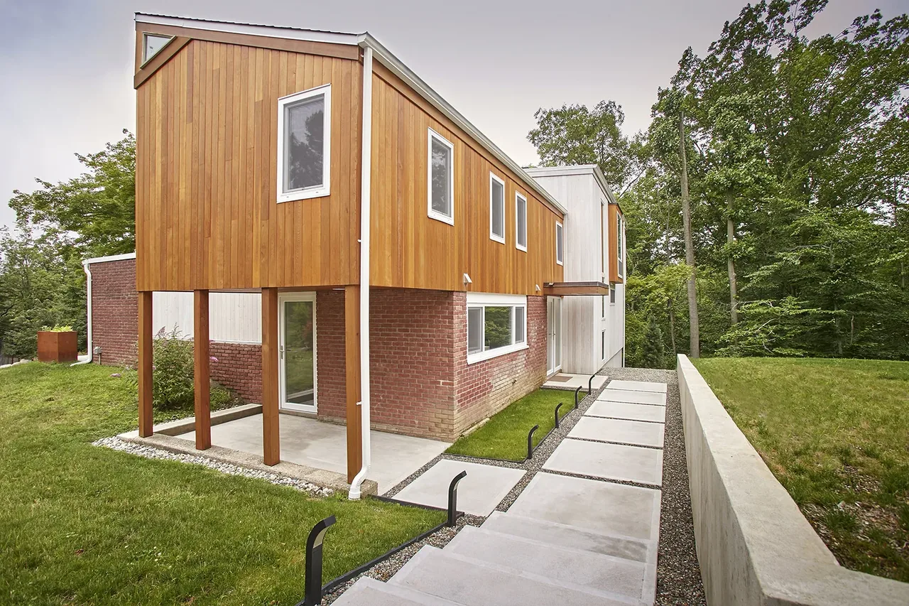 Mid-century to modern renovation featuring a two-tone facade with raised wood siding and rectangular windows.