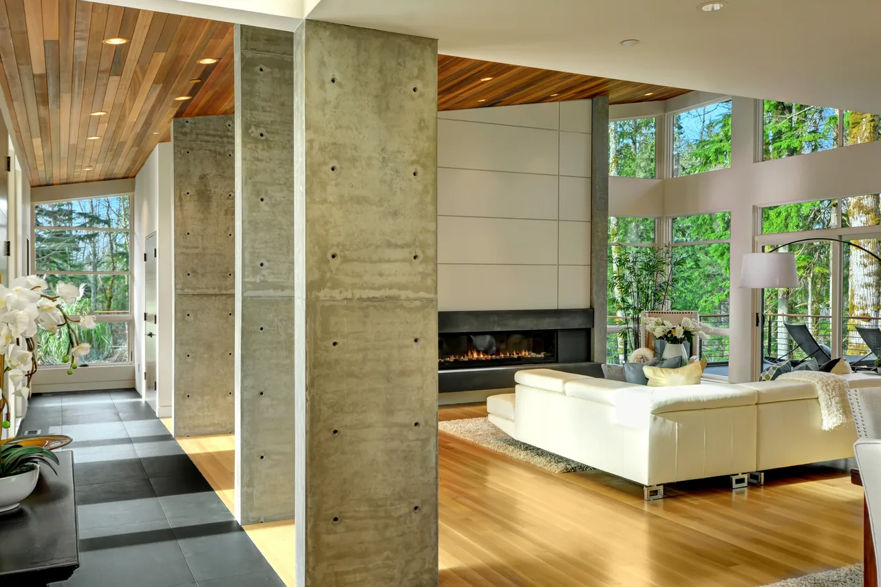 Living room of Pavilion in the Woods with floor-to-ceiling windows and concrete columns by Baylis Architecture in Seattle.